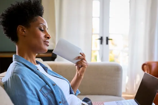 A woman sat on a sofa fanning herself